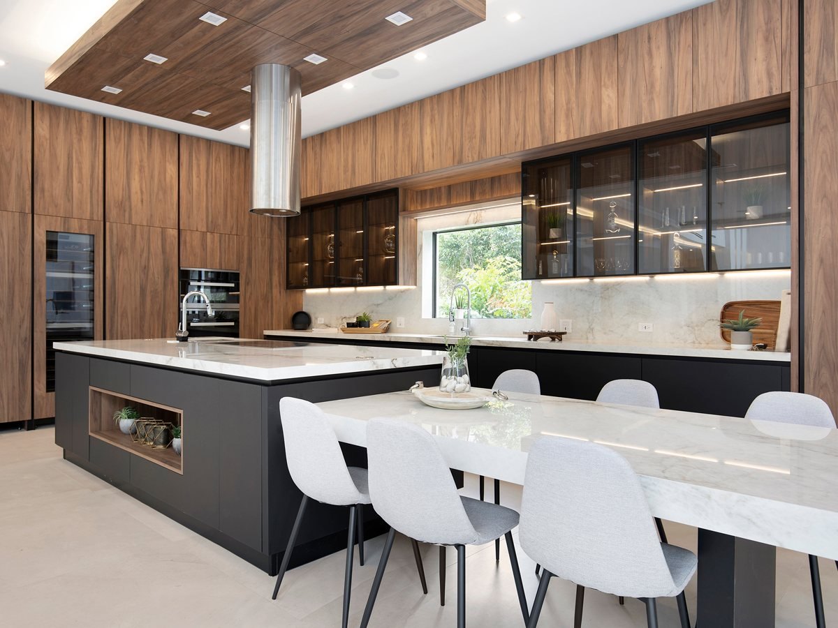 Adornus walnut-tone slab kitchen with a black island and marble-look counters — manufacturer photo