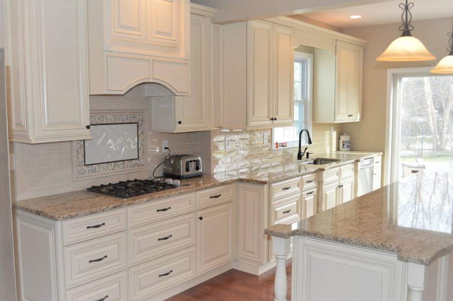 21st Century Perla Cream raised-panel kitchen with a granite island — manufacturer photo