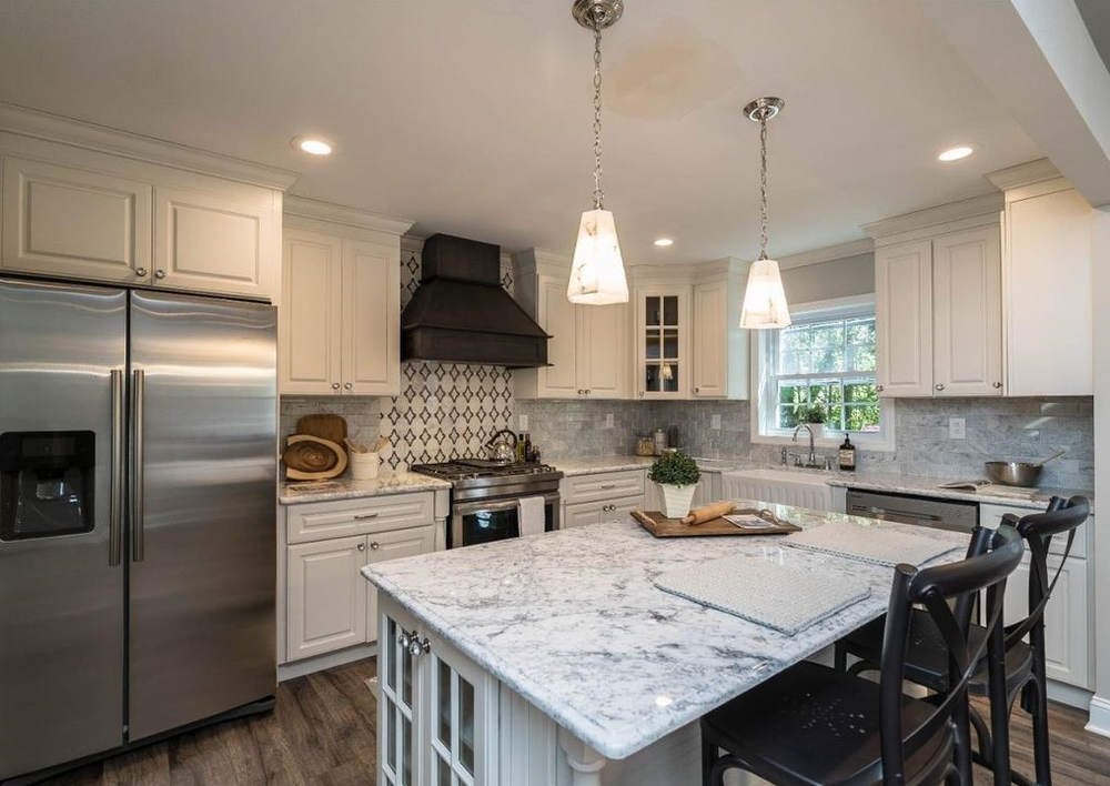 FGM white shaker kitchen with a marble-look island and a black range hood — manufacturer photo