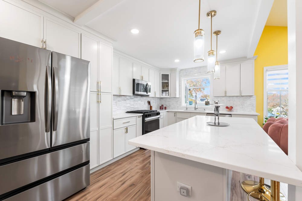 FGM white kitchen with a quartz island and brass pendants — manufacturer photo