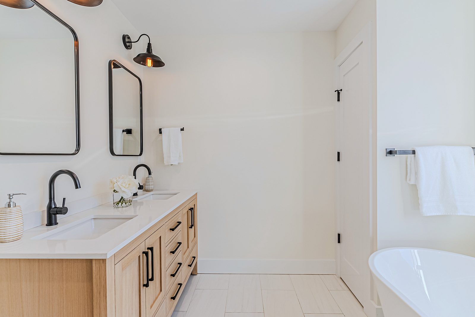 White-oak and navy bathroom vanities with a freestanding tub and black fixtures — photo 8