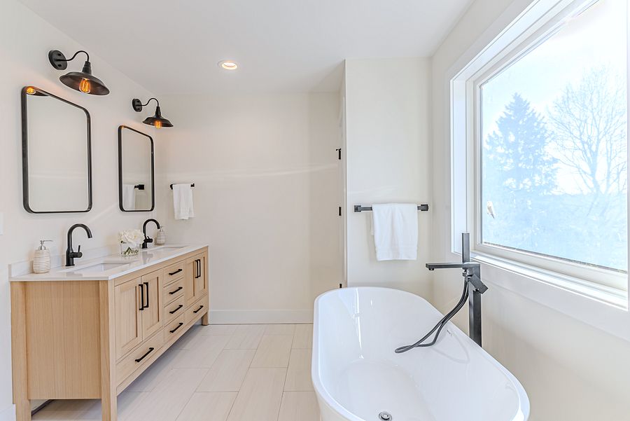 Project 157: White-oak and navy bathroom vanities with a freestanding tub and black fixtures