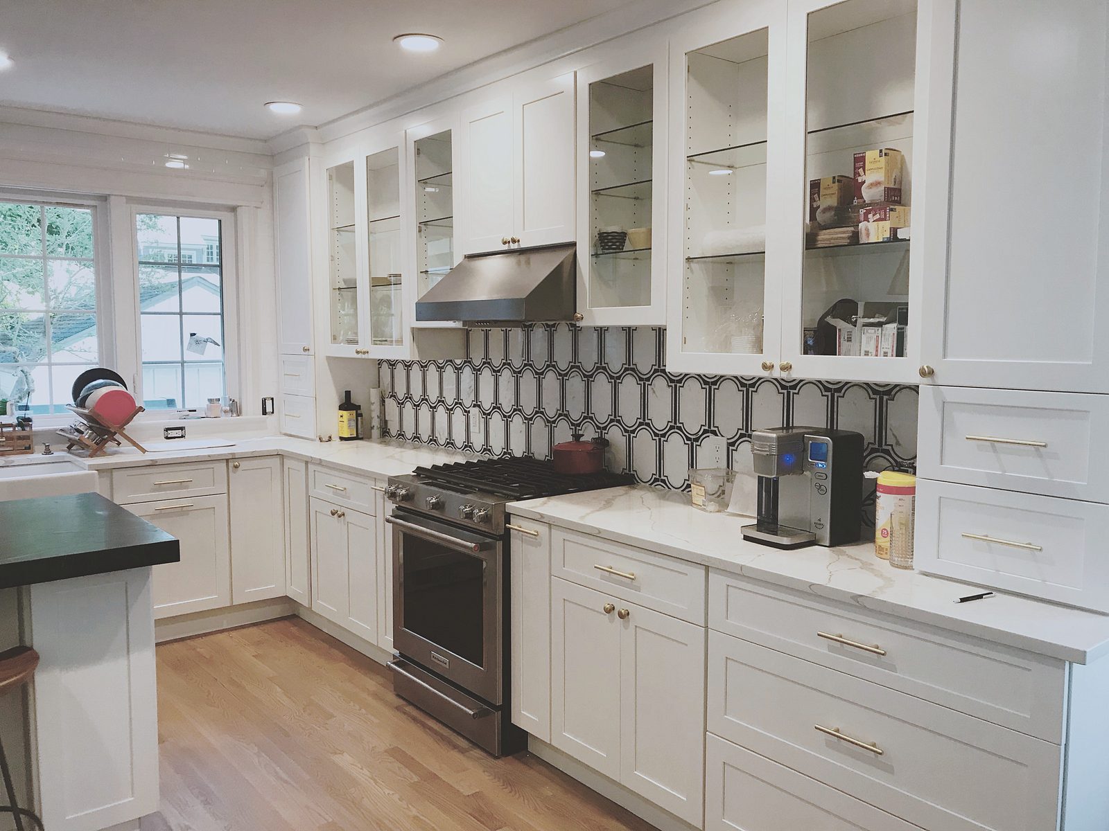 Gray hexagon tile backsplash, brass cone pendants — Fabuwood Galaxy in Frost with a dark honed counter and hex tile