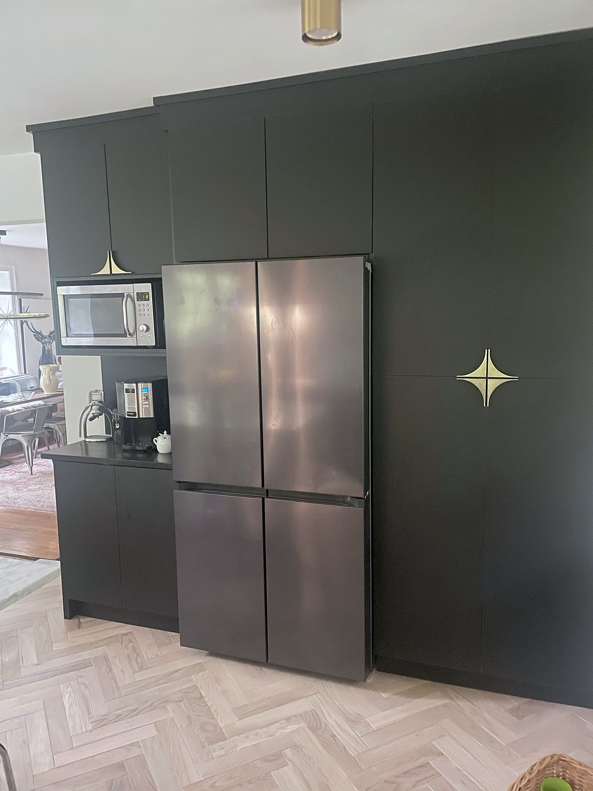 Black range, black-stainless refrigerator — Fabuwood Luna kitchen in matte black with a Dove island and a herringbone floor