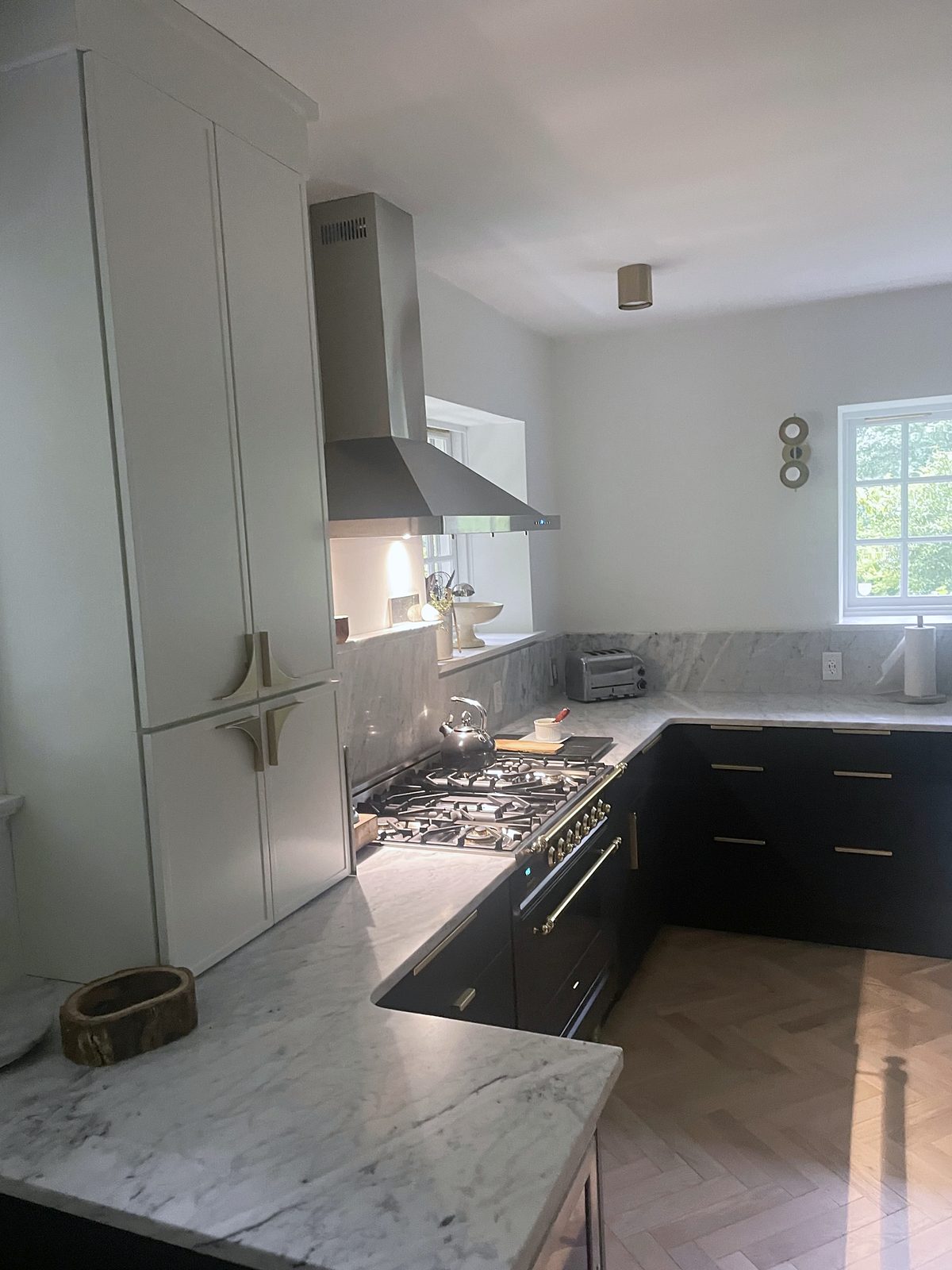 Brass bar pulls; light herringbone wood floor — Fabuwood Luna kitchen in matte black with a Dove island and a herringbone floor