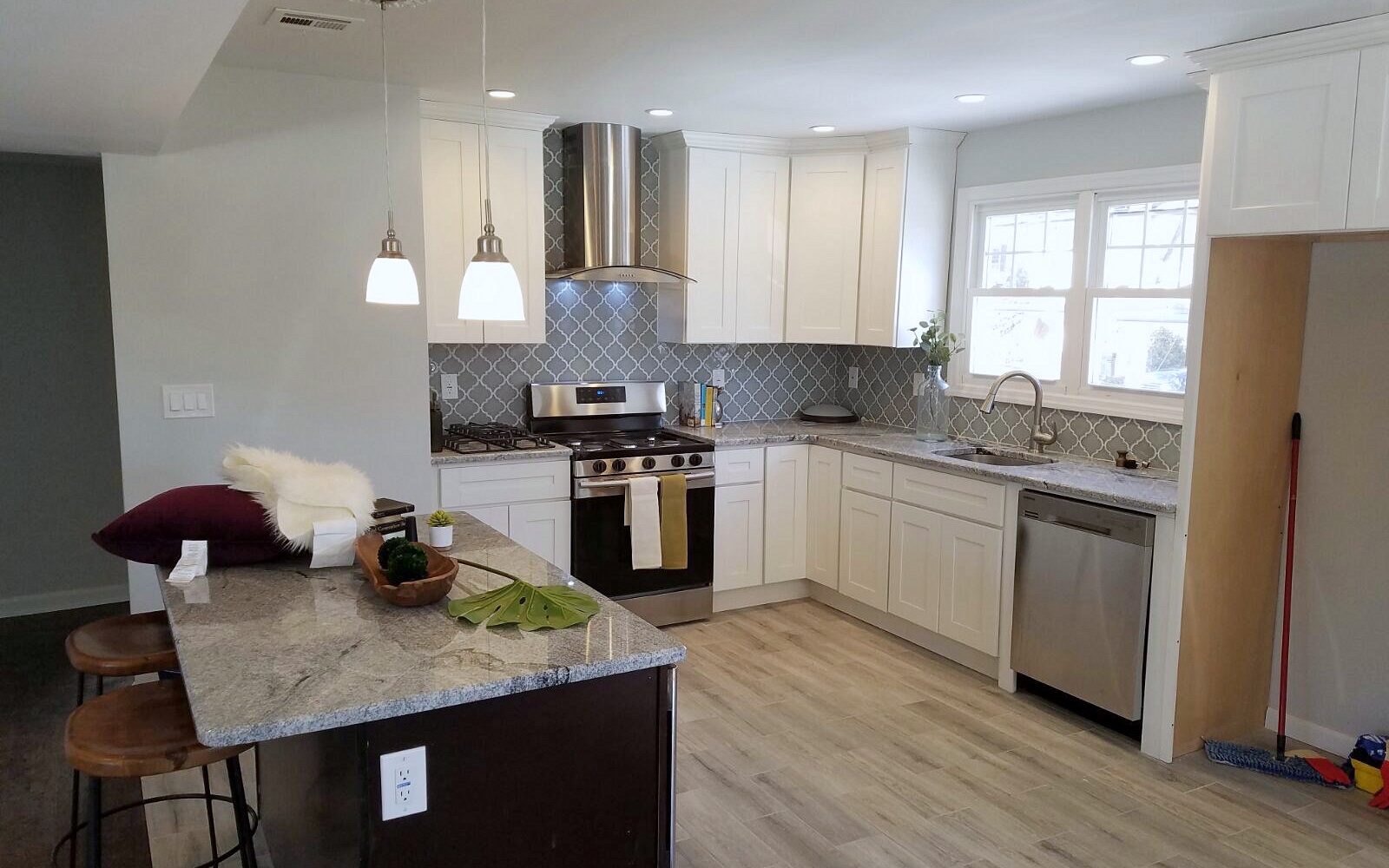Espresso island with a veined white quartz top — FGM Mercury White kitchen with an espresso island and a mosaic backsplash