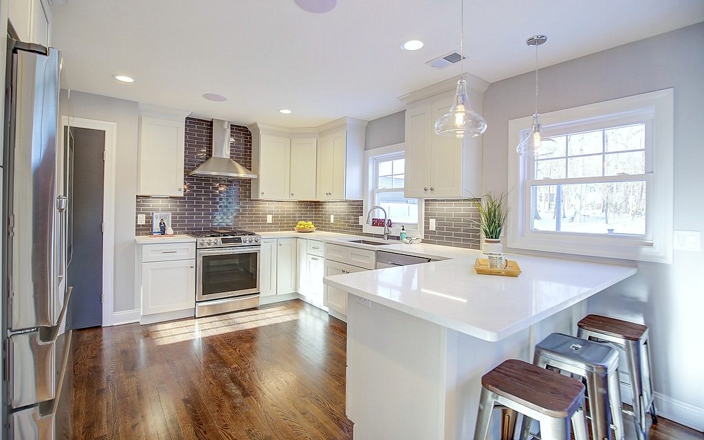 Open dining room with a crystal drum pendant — FGM Mercury White kitchen with gray subway tile and an open dining room