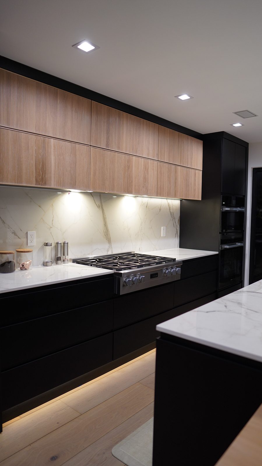 Oak slab uppers over the black handleless base cabinets