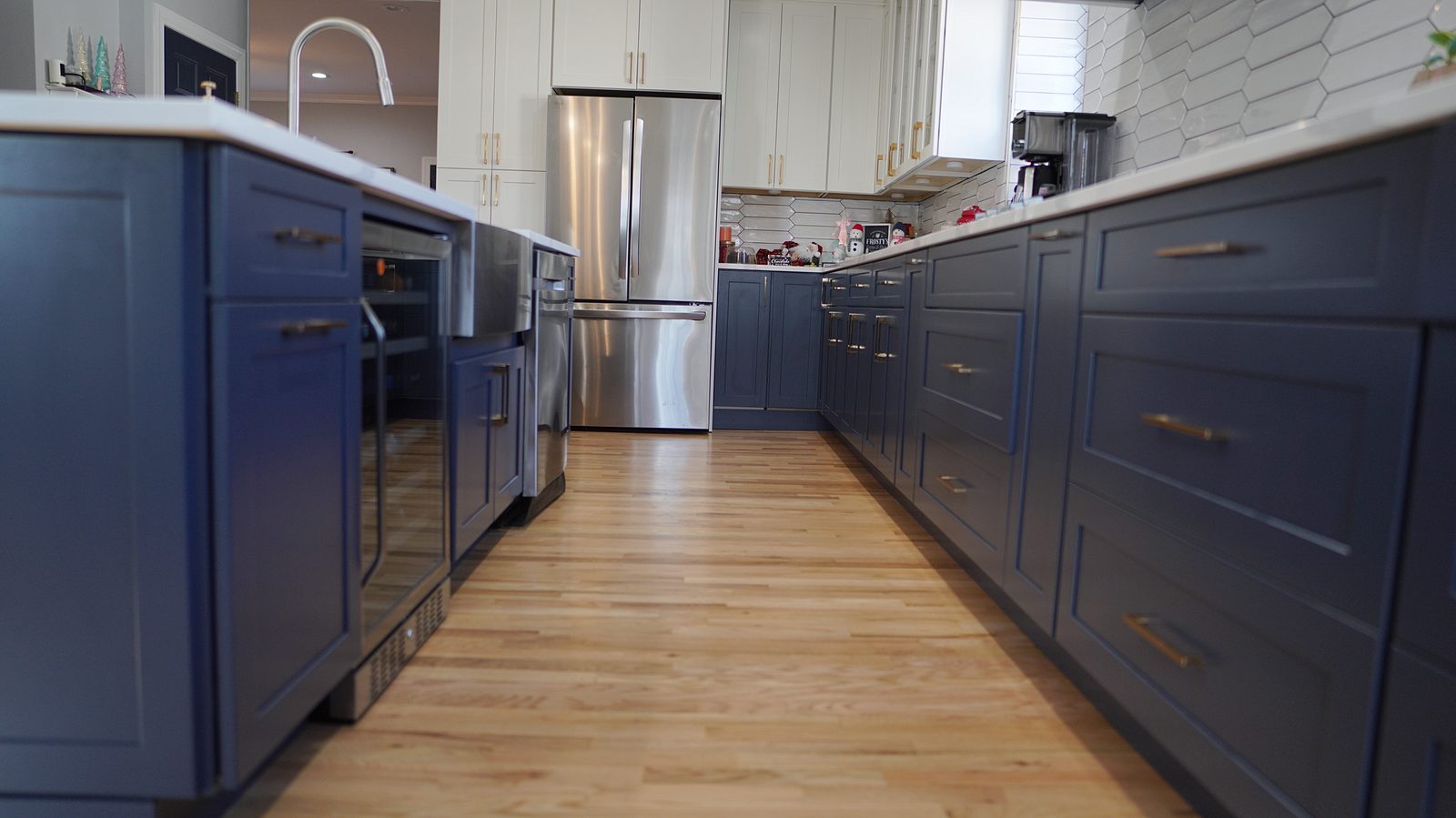 Navy base cabinets with brass pulls along the range wall