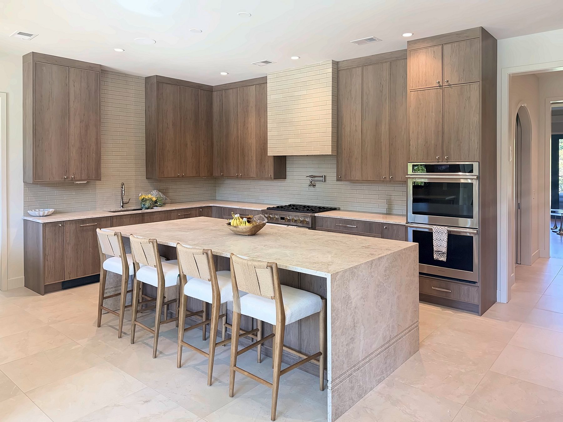 Custom thin-shaker kitchen in Tafisa Salt of the Earth with a beige stone waterfall island and five stools