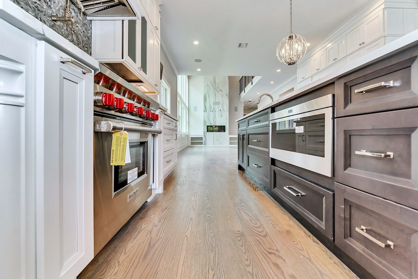 White shaker kitchen with a long charcoal island in a two-story great room — photo 8
