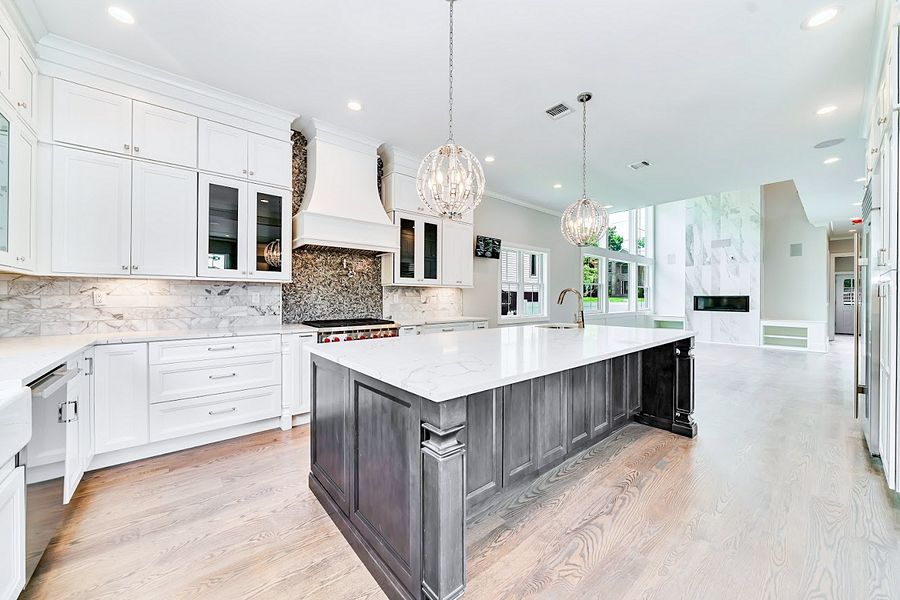 Project 142: White shaker kitchen with a long charcoal island in a two-story great room