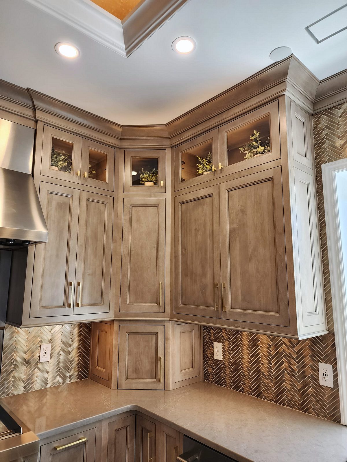Pro-style range, stainless chimney hood, built-in refrigerator — Shiloh Aspen inset kitchen in a brown stain with a lit bar wall and a butler’s pantry