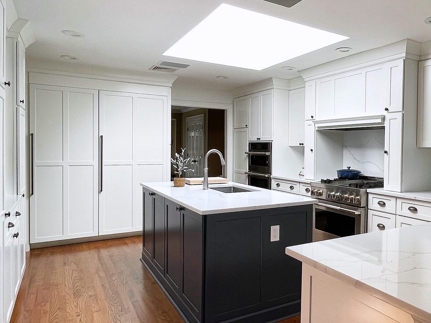 White quartz, marble-look slab — Shiloh Hanover kitchen in Aspen with a black island and a skylight