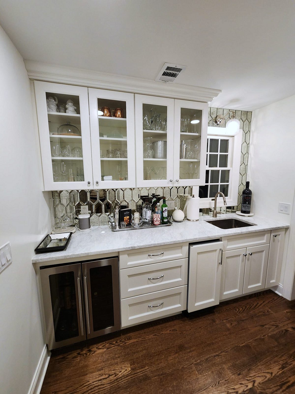 Black cage pendants, brass hardware — Shiloh Heritage beaded-inset kitchen under a vaulted ceiling with a curved hood