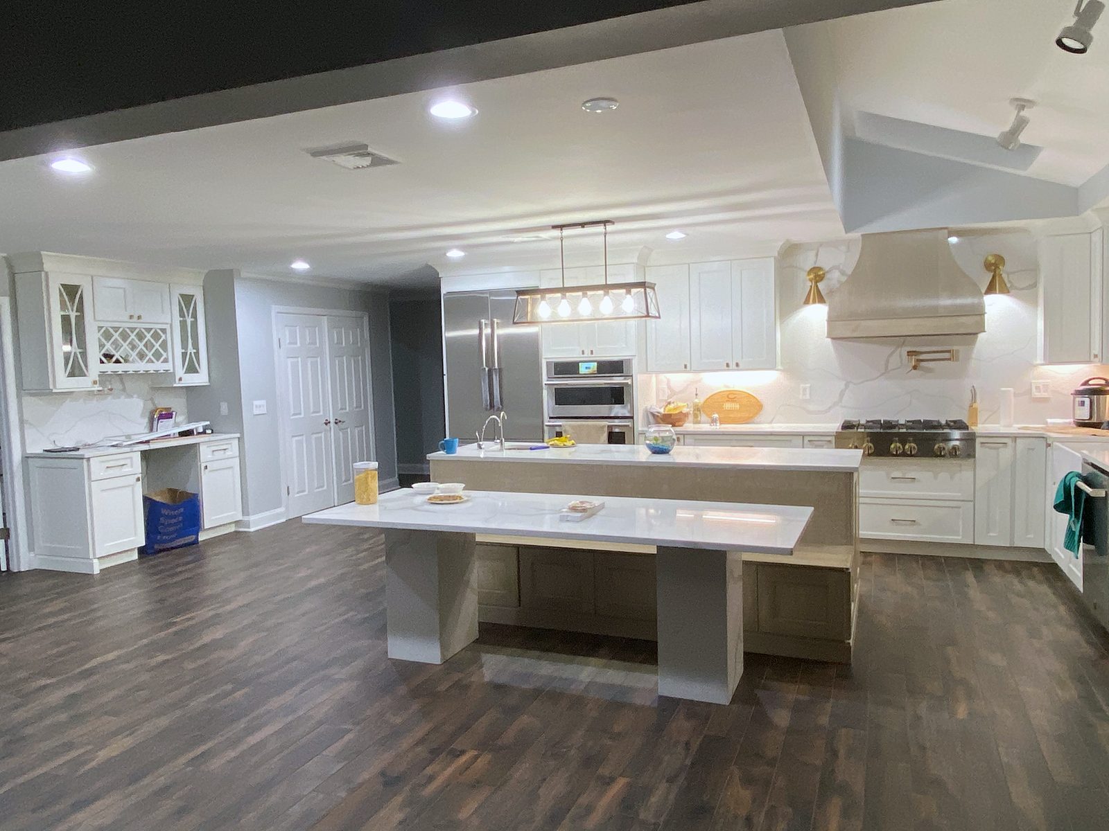 Two-level island with a built-in bench — Shiloh Heritage kitchen in Polar and Seagull with a bench island and a gray wood hood