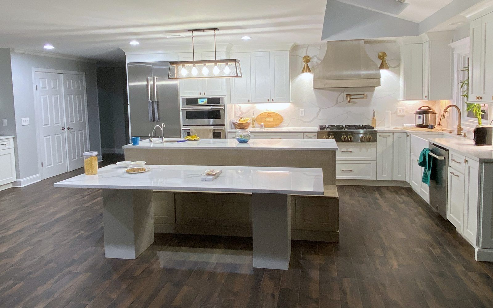 Gray-stained wood hood with brass sconces — Shiloh Heritage kitchen in Polar and Seagull with a bench island and a gray wood hood