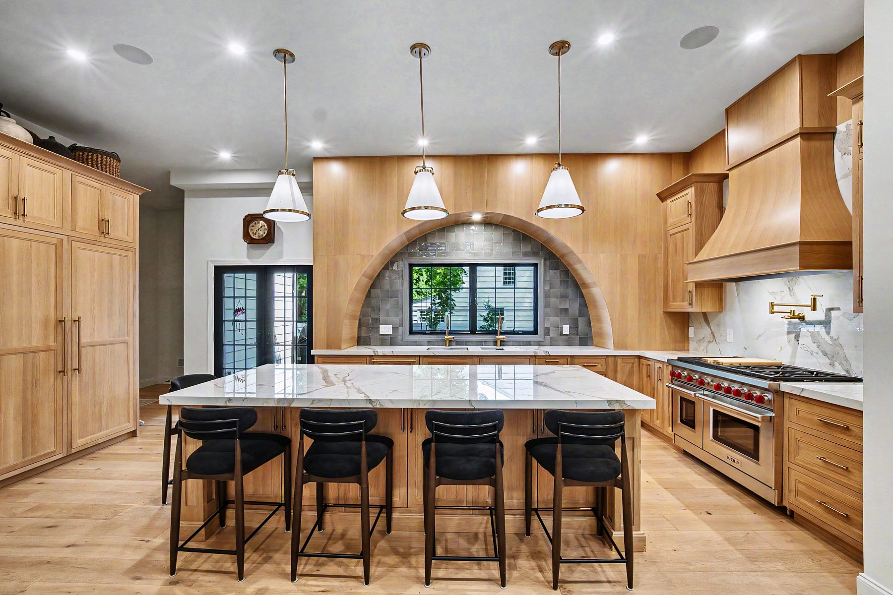Rift white oak kitchen with arched niche over the sink, Calacatta quartz island and Wolf range