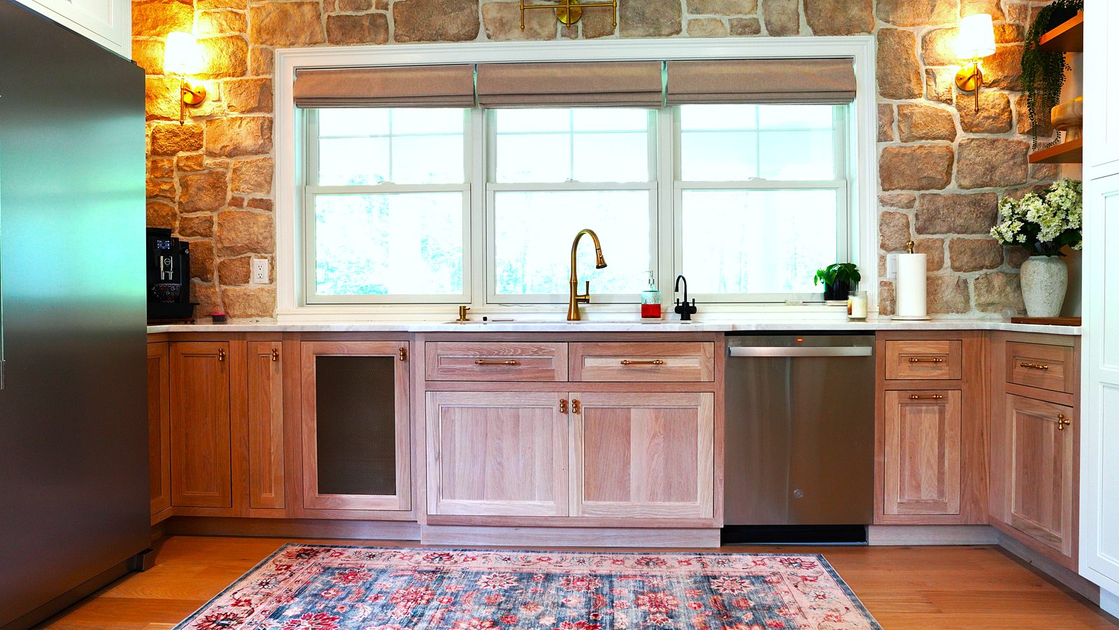 Sink wall with the stone accent wall, brass faucet and stainless dishwasher