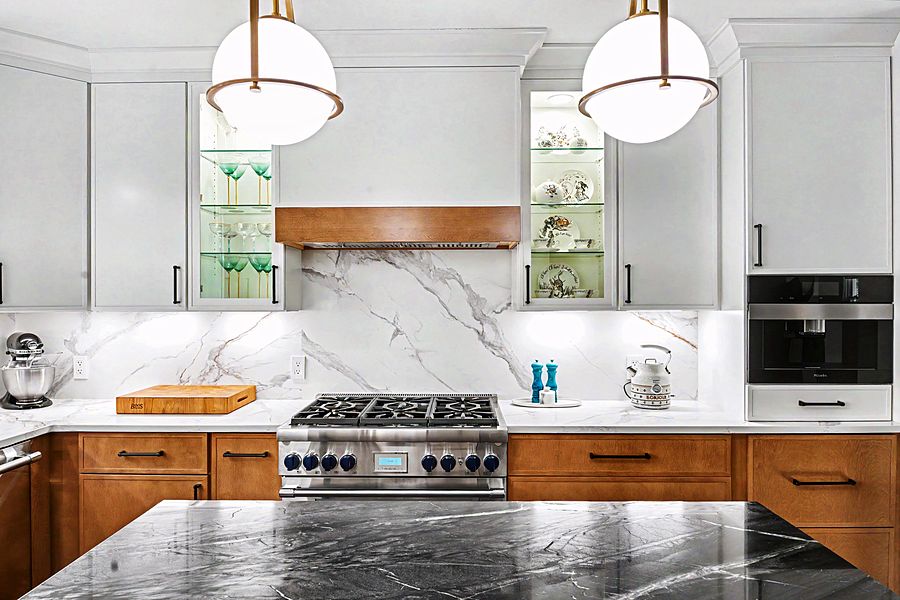 Two-tone white and natural wood kitchen with a black marble waterfall island