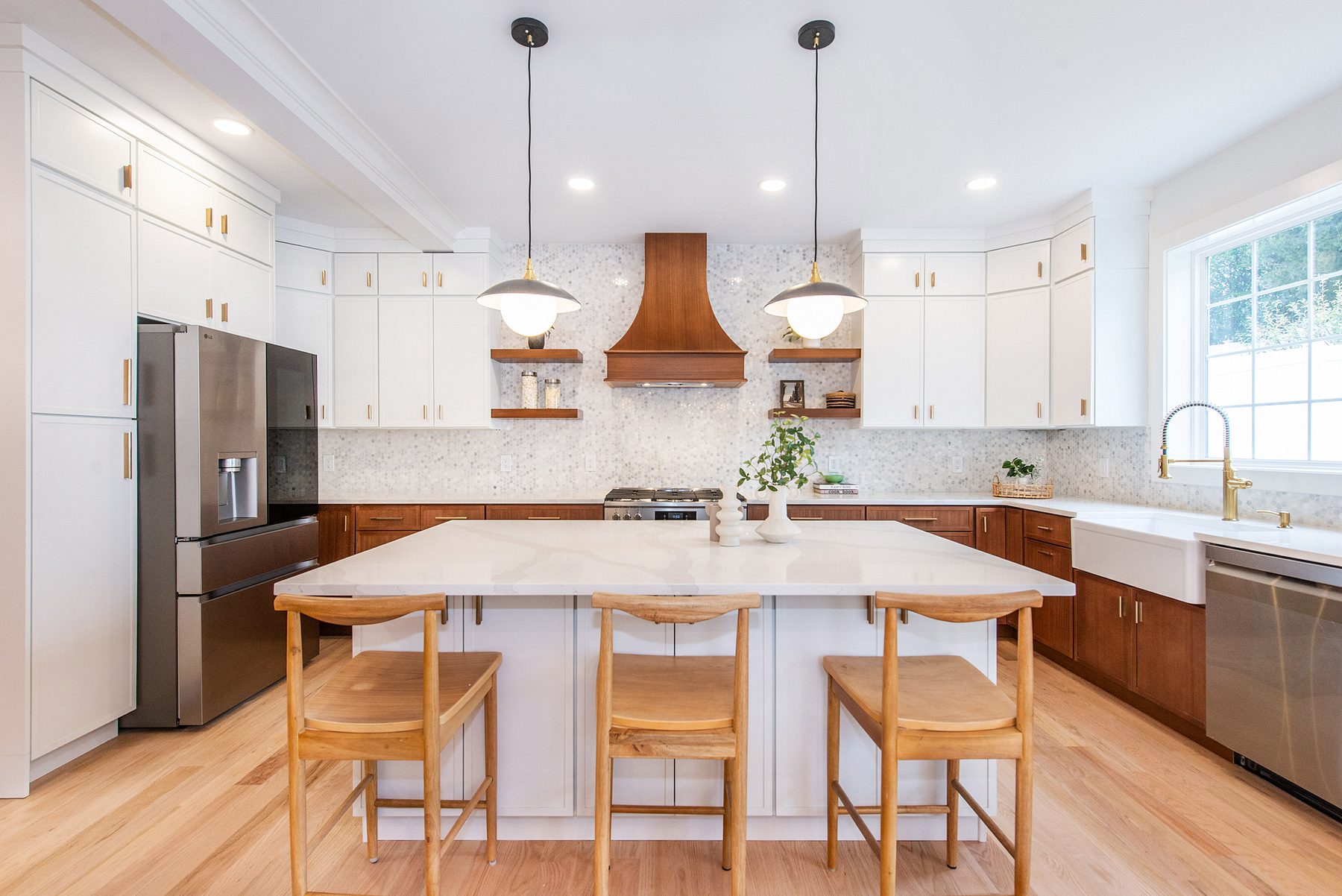 New-construction kitchen in Verona with white shaker uppers, stained-wood base cabinets, a wood hood and a white island with three wood stools