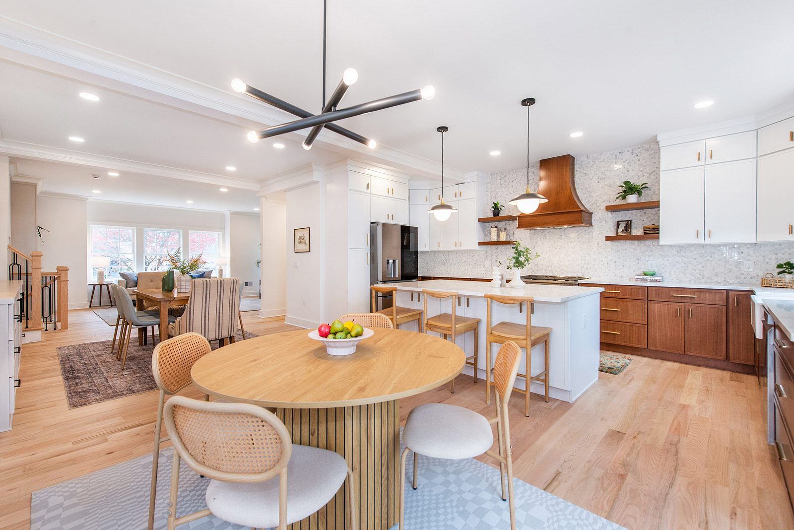 Round oak dining table between the kitchen and the glass doors