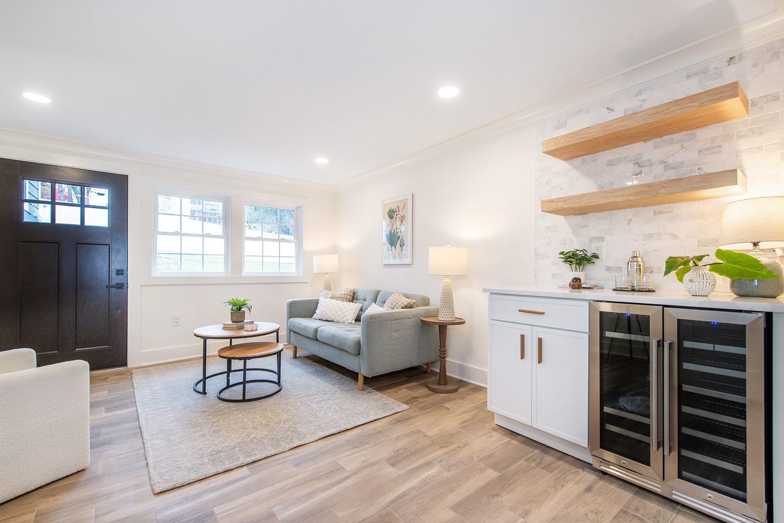 Beverage bar with two glass-door fridges and floating shelves off the living room