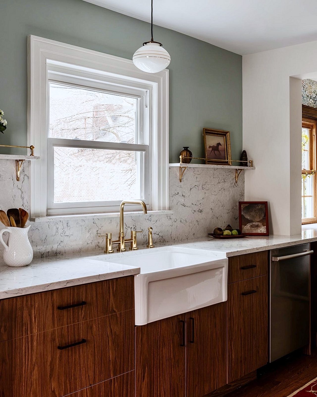 Marble-look quartz counters run full height as the backsplash — Walnut slab kitchen with marble-look quartz, a farmhouse sink and brass