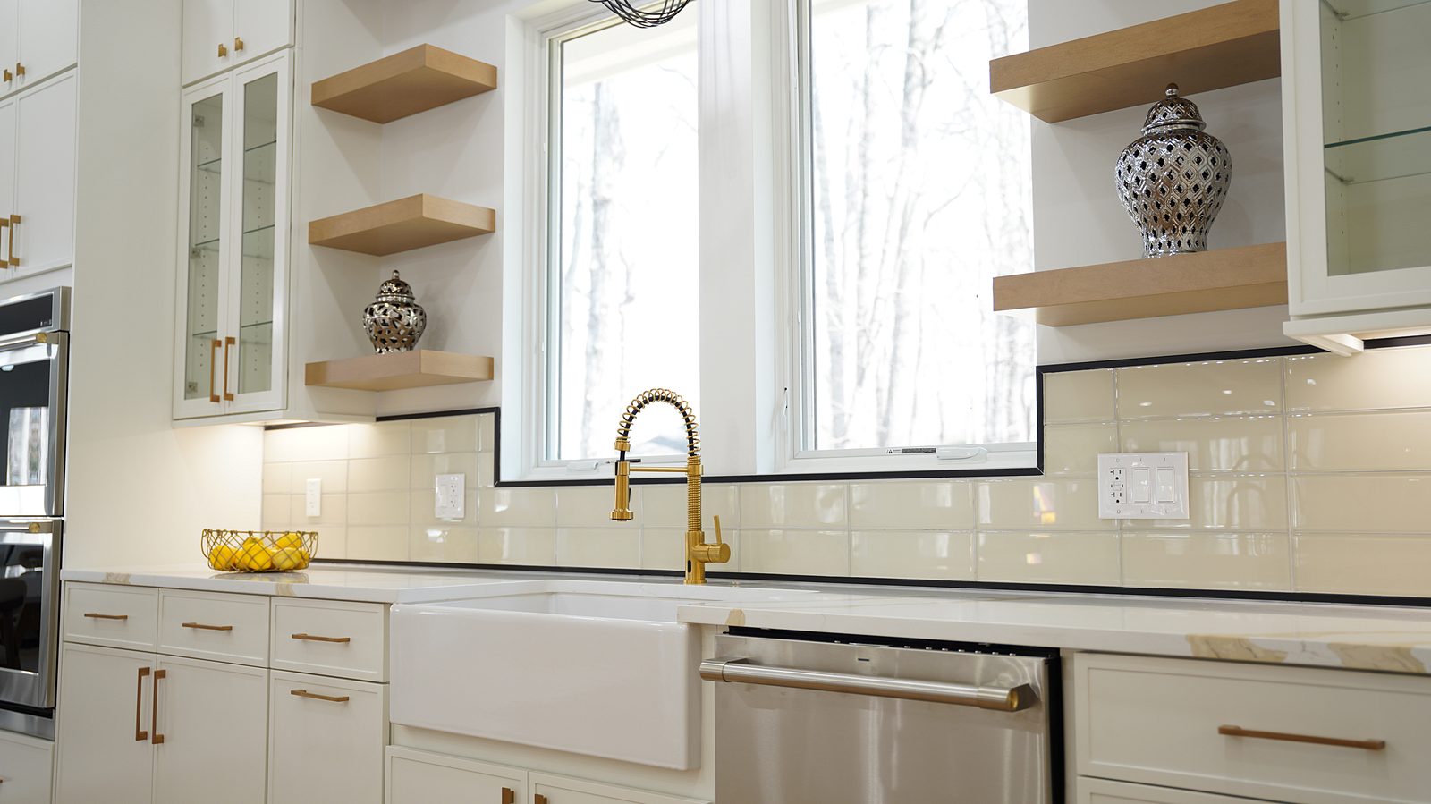 Apron-front sink with a gold faucet, glass-front uppers and oak floating shelves