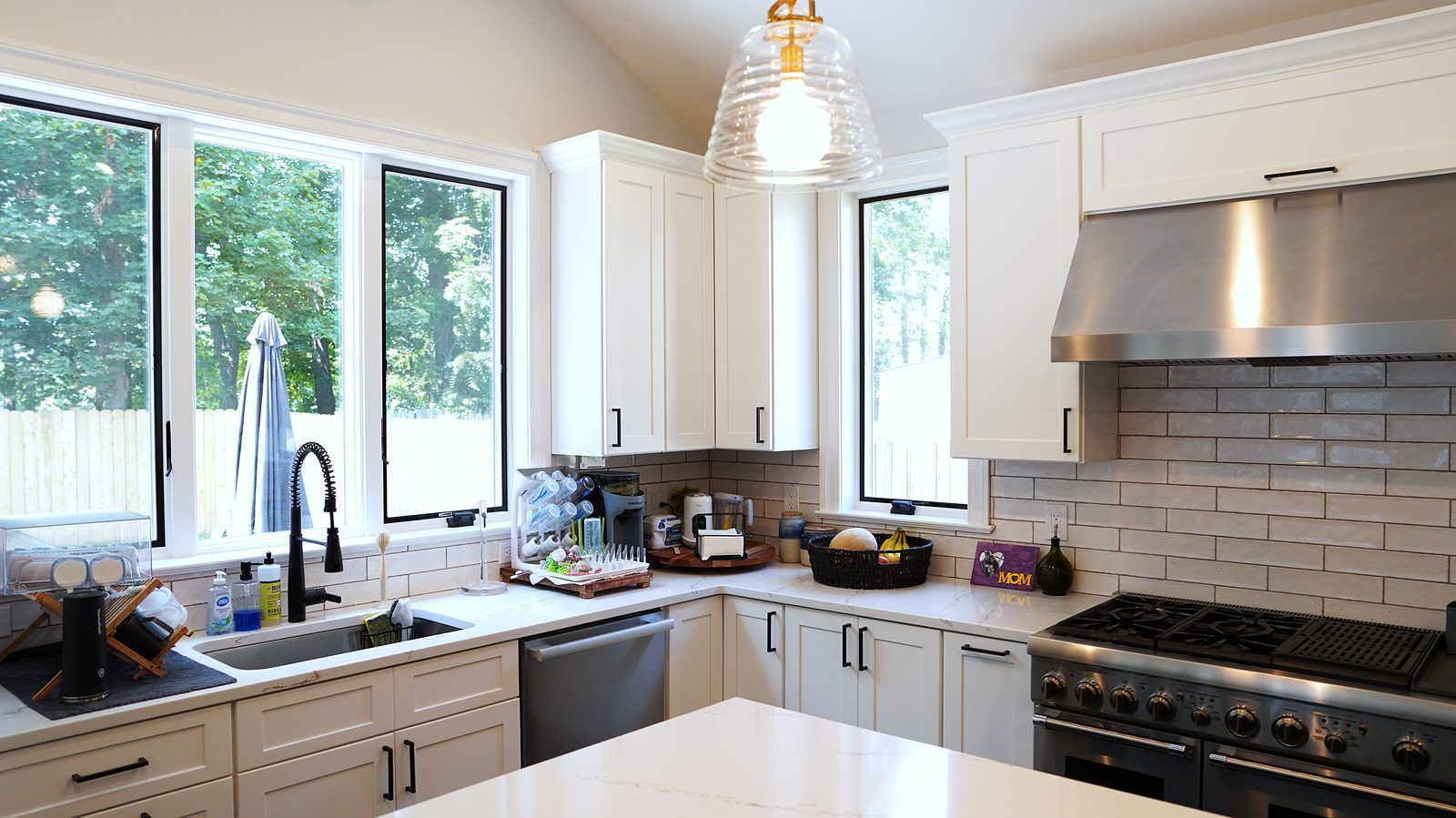 Sink under the black-framed windows with the gray subway backsplash