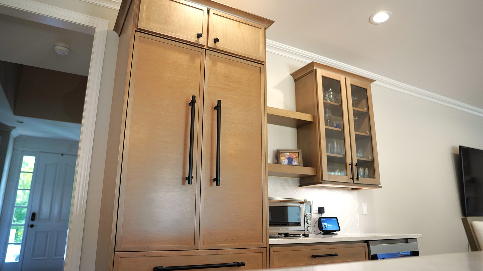 Light-oak pantry wall with glass-front uppers and brass pulls
