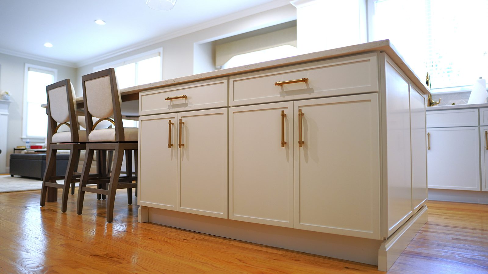 White shaker island with brass pulls and a marble-look quartz top