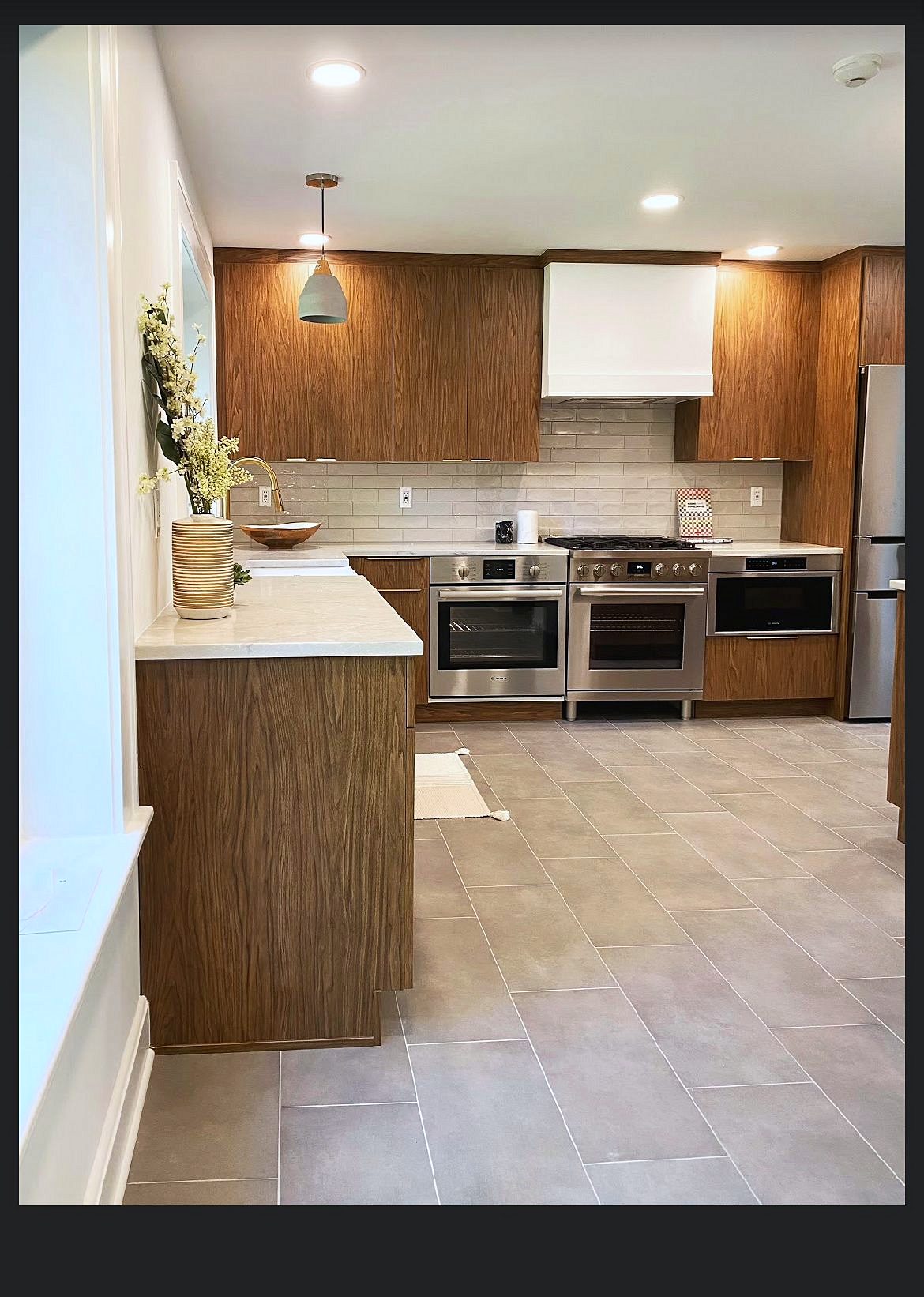Wood-grain slab kitchen with brass pulls and a mirrored wine bar