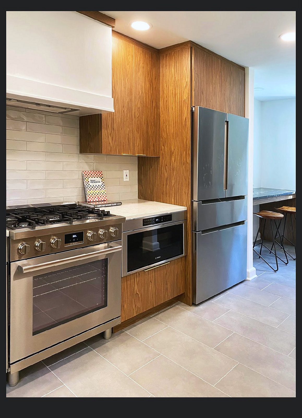White quartz, large-format tile backsplash, plaster-look hood — Wood-grain slab kitchen with brass pulls and a mirrored wine bar
